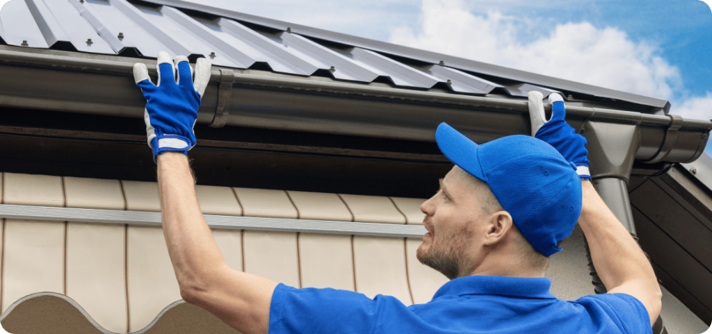 Homem instalando uma calha em um telhado